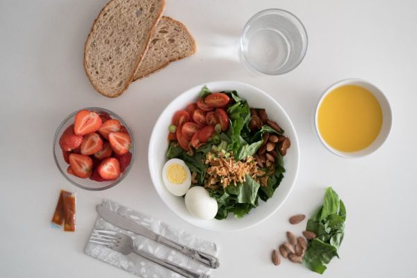 Top view of a nutritious breakfast with salad, eggs, bread, and juice, perfect for a healthy start.